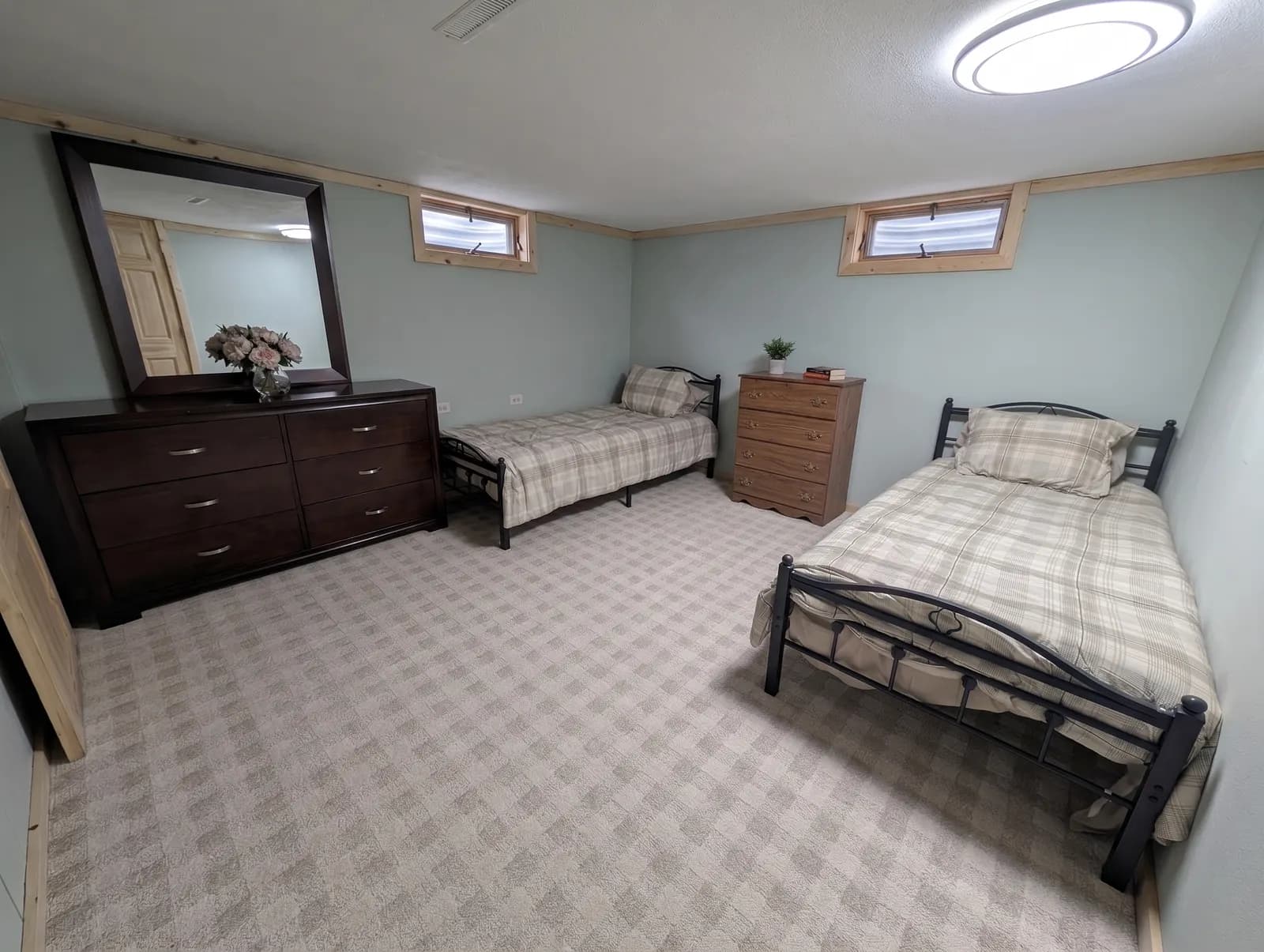 Furnished bedroom with two twin beds, a dresser, and a large mirror