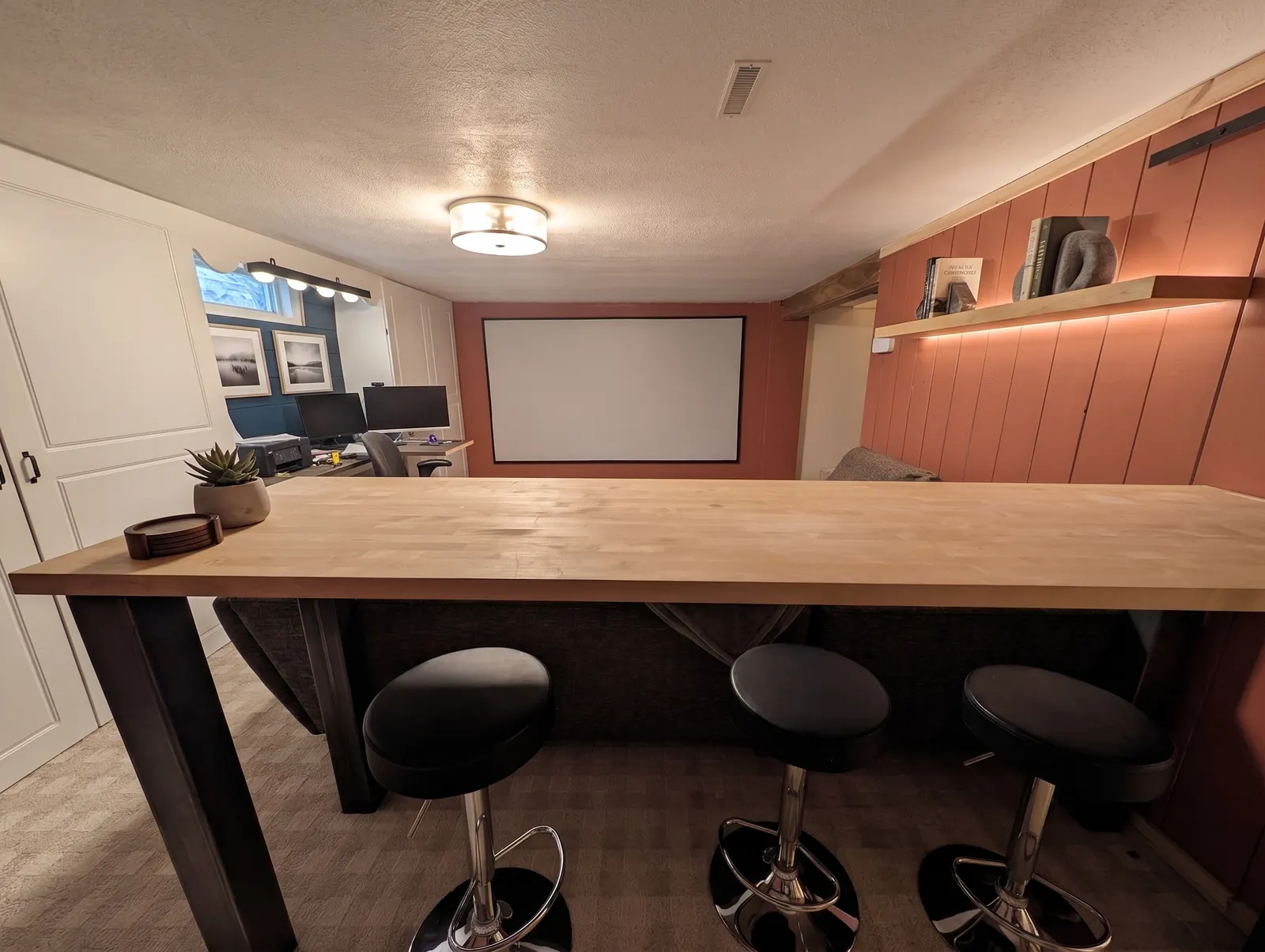 Community room with bar-height seating, a projector screen, and a study desk